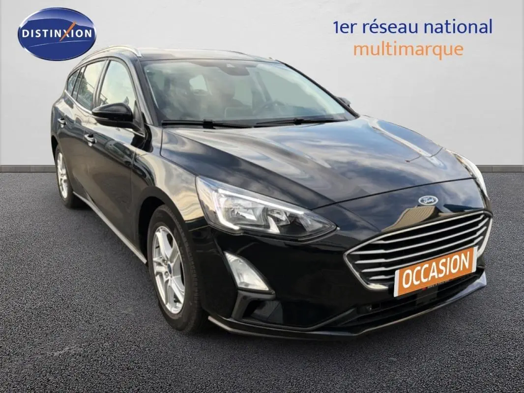 Ford Focus SW noire vue en 3/4 avant droit avec barres de toit et jantes alliage 16 pouces.