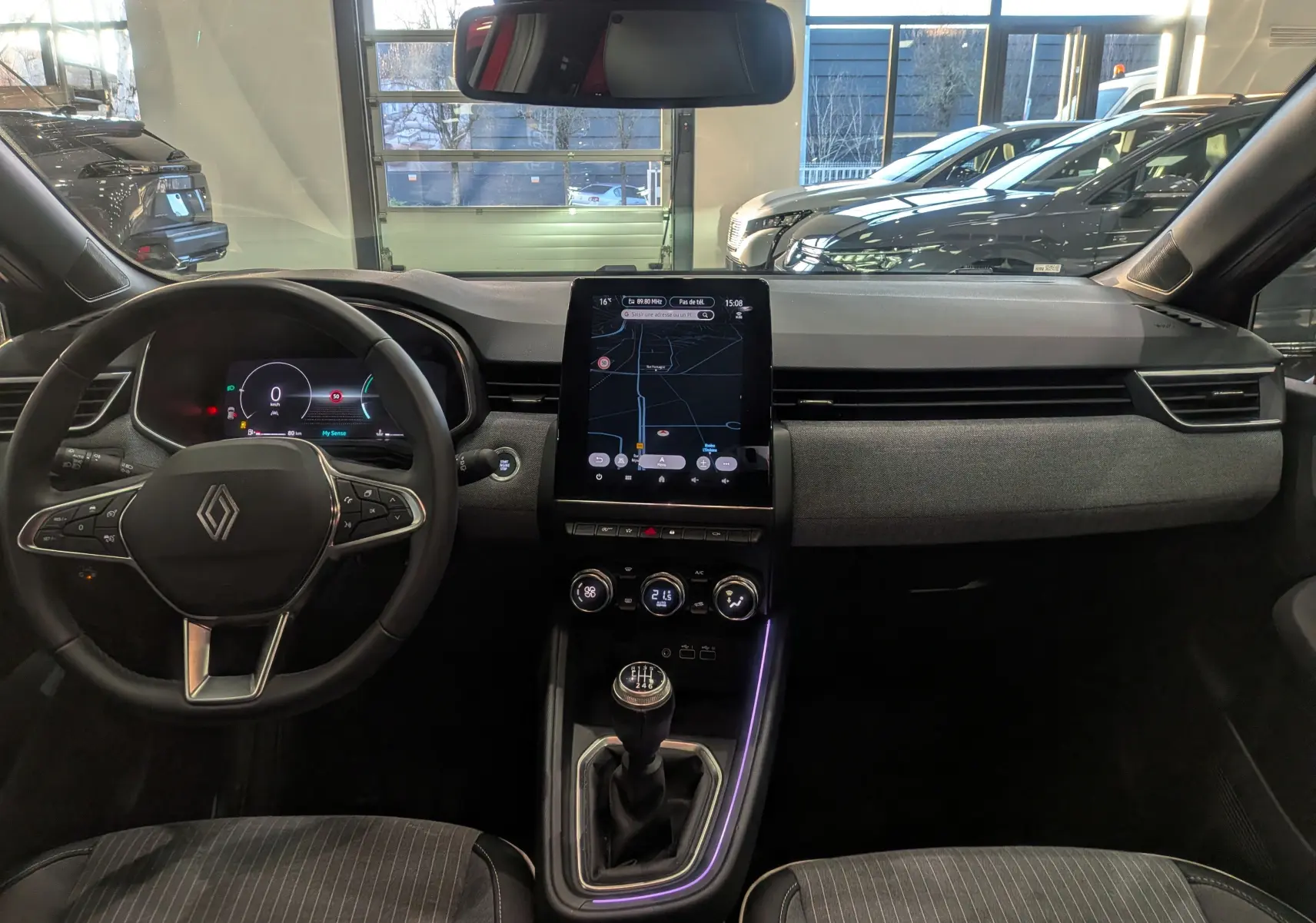 Vue intérieure avant de la Renault Clio V rouge Flamme, avec tableau de bord numérique et écran tactile central vertical.