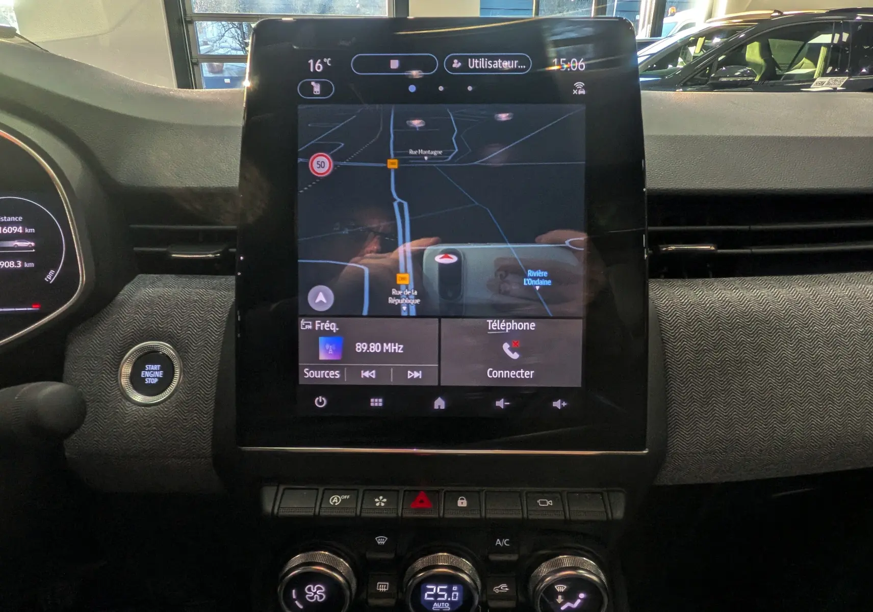 Vue rapprochée de l’écran tactile central et de la console de la Renault Clio V Rouge Flamme, affichant la navigation et la climatisation.