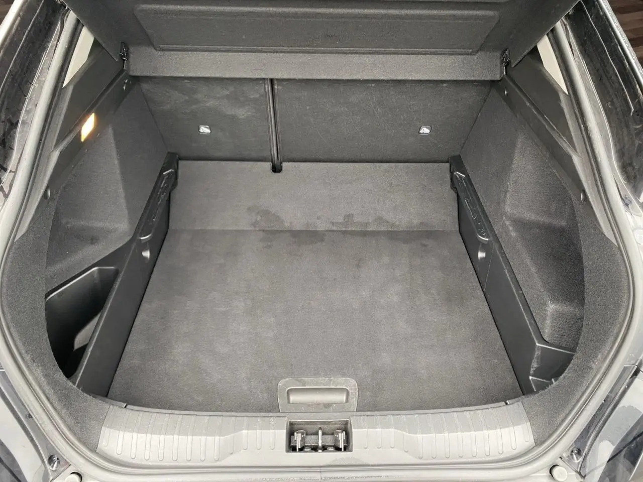 Coffre ouvert du Renault Arkana noir 2024, vue de dessus montrant un espace de rangement propre et spacieux.