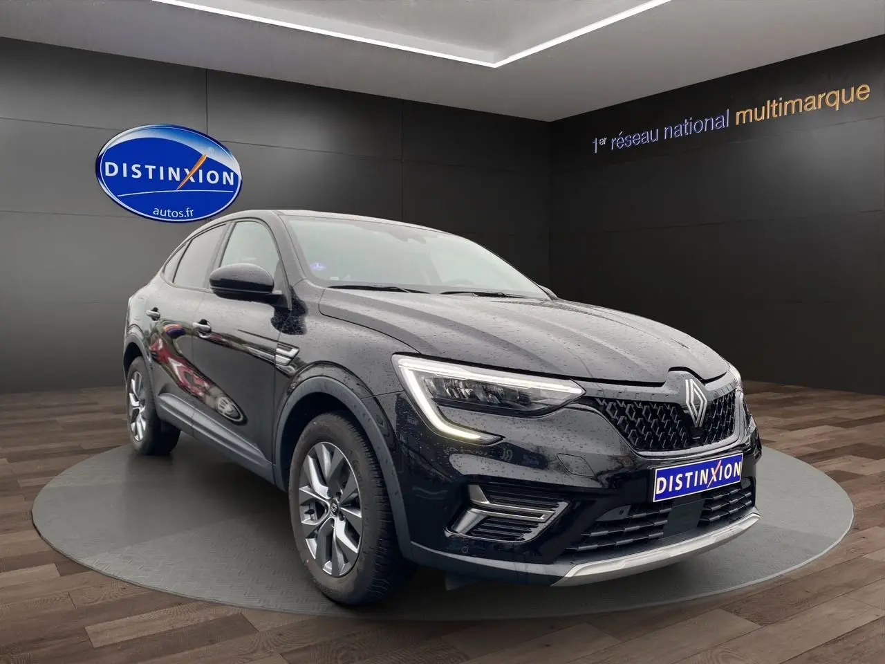 Renault Arkana noir vue 3/4 avant droit, avec calandre distinctive et feux LED allumés, en showroom intérieur.