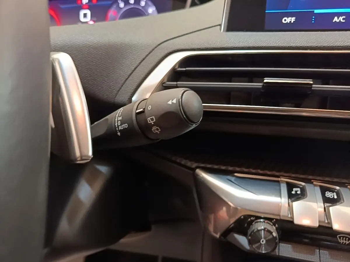 Gros plan sur la commande d’essuie-glace à gauche du volant dans l’habitacle du Peugeot 3008 noir 2022.