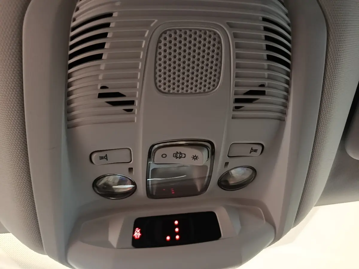 Vue en gros plan du plafonnier intérieur gris clair du Peugeot 3008 2022 avec boutons d’éclairage et détecteur intégré.