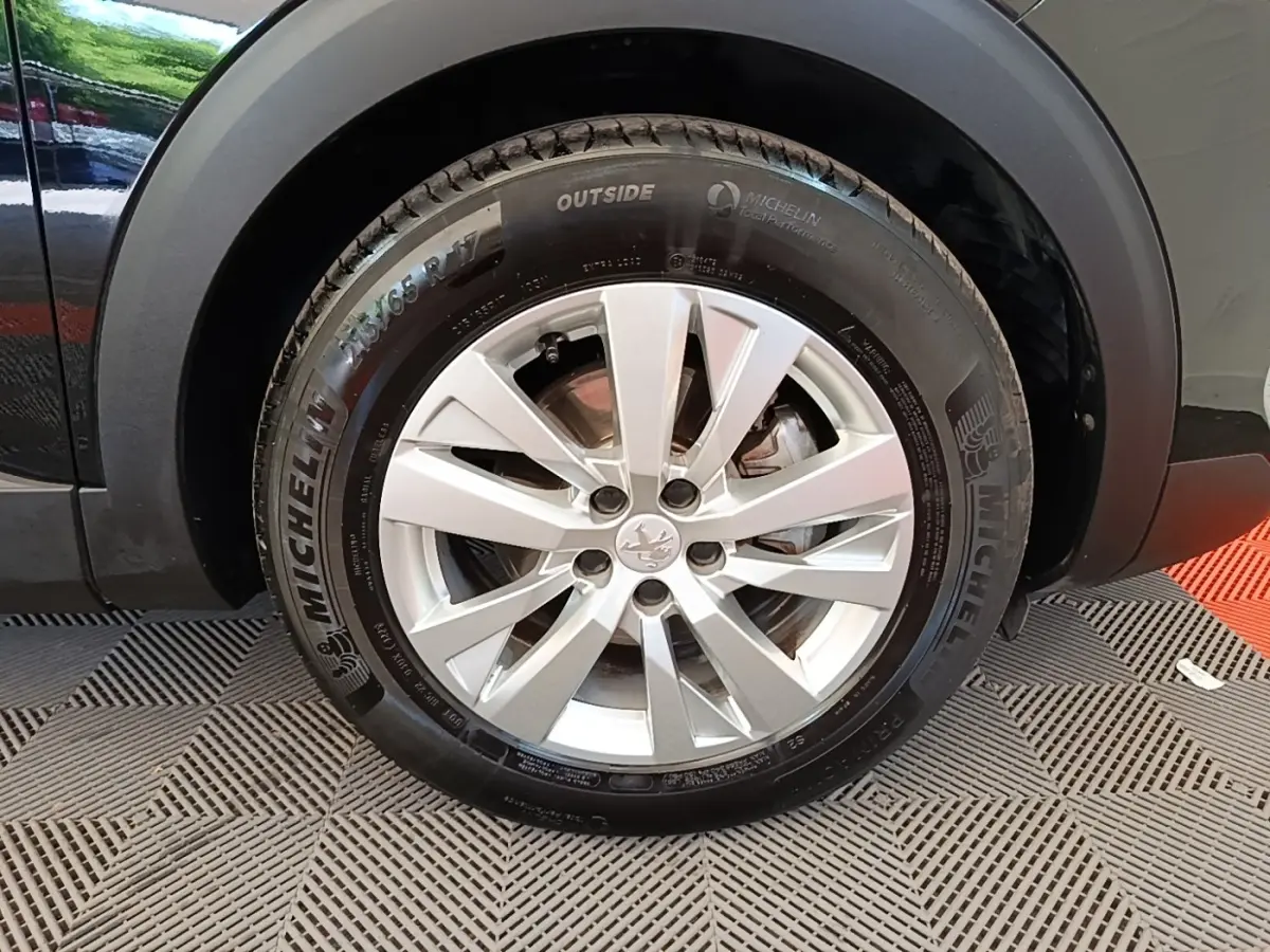 Gros plan sur la roue avant gauche du Peugeot 3008 noir, mettant en valeur la jante alliage et le pneu Michelin.