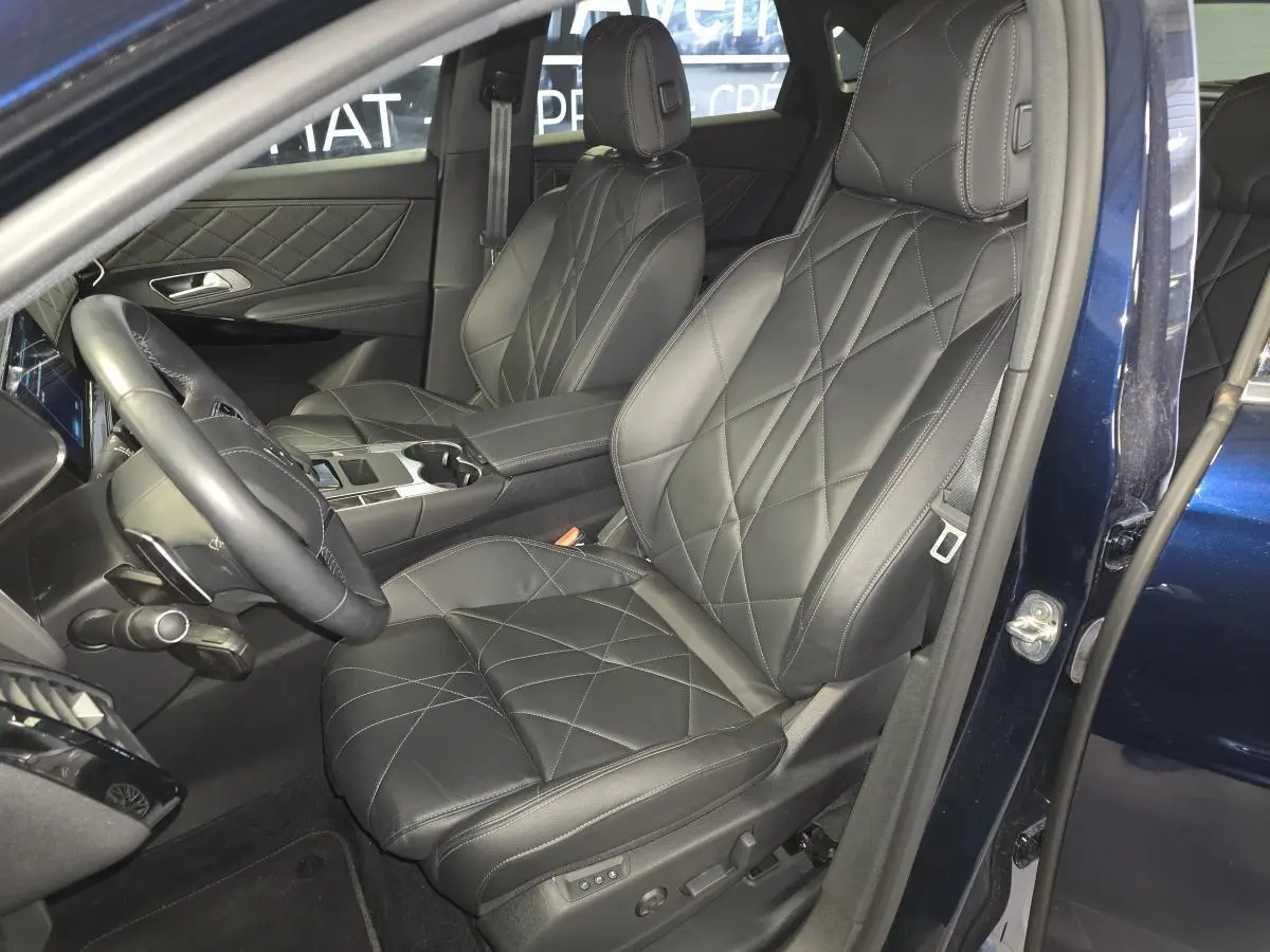 Intérieur avant du DS7 Crossback E-Tense 2024, sièges en cuir noir avec surpiqûres et porte ouverte côté conducteur bleu métallisé.