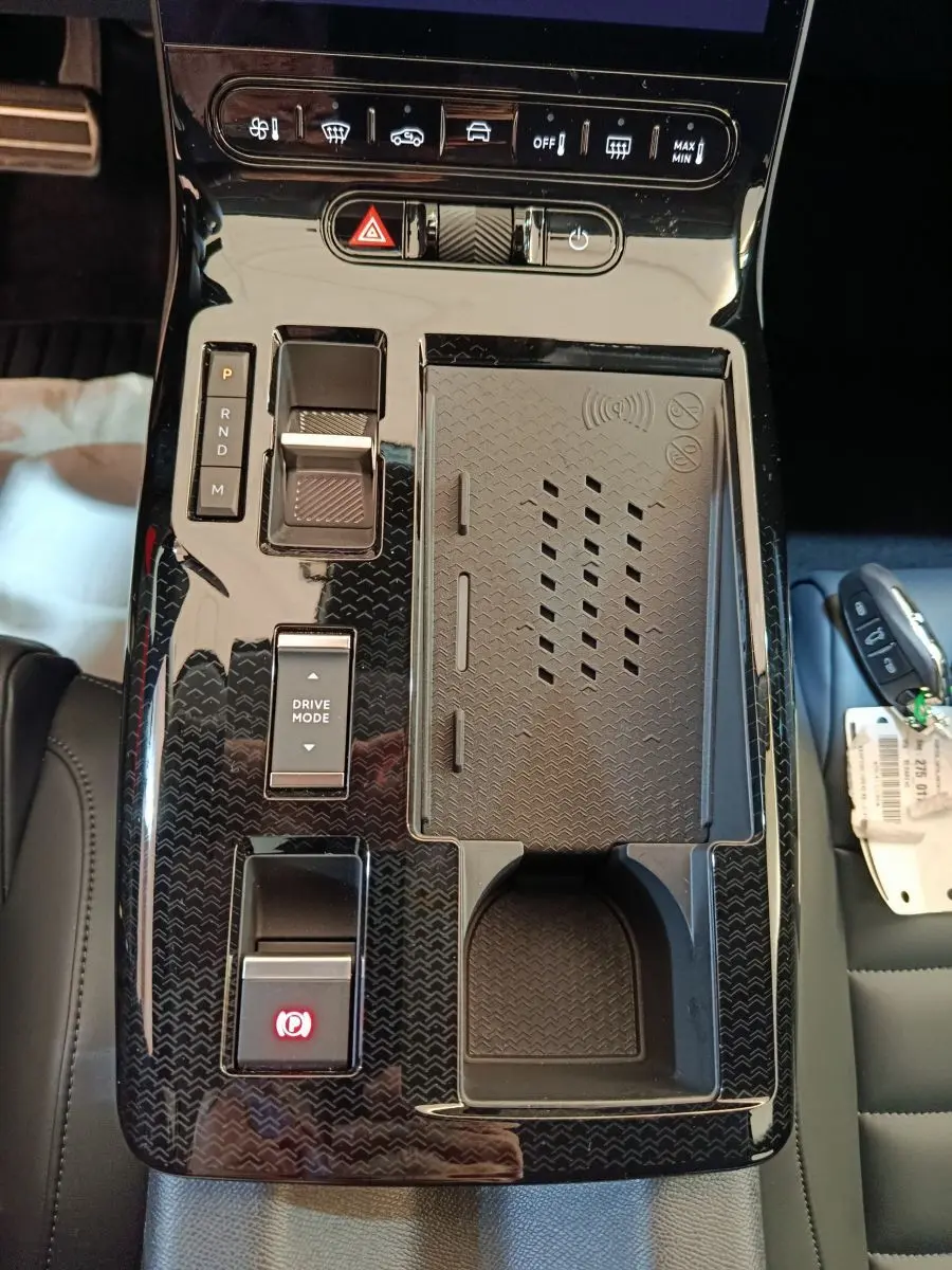 Vue plongeante sur la console centrale noire brillante du Citroën C5 Hybride 2026 avec commandes tactiles et porte-gobelet.