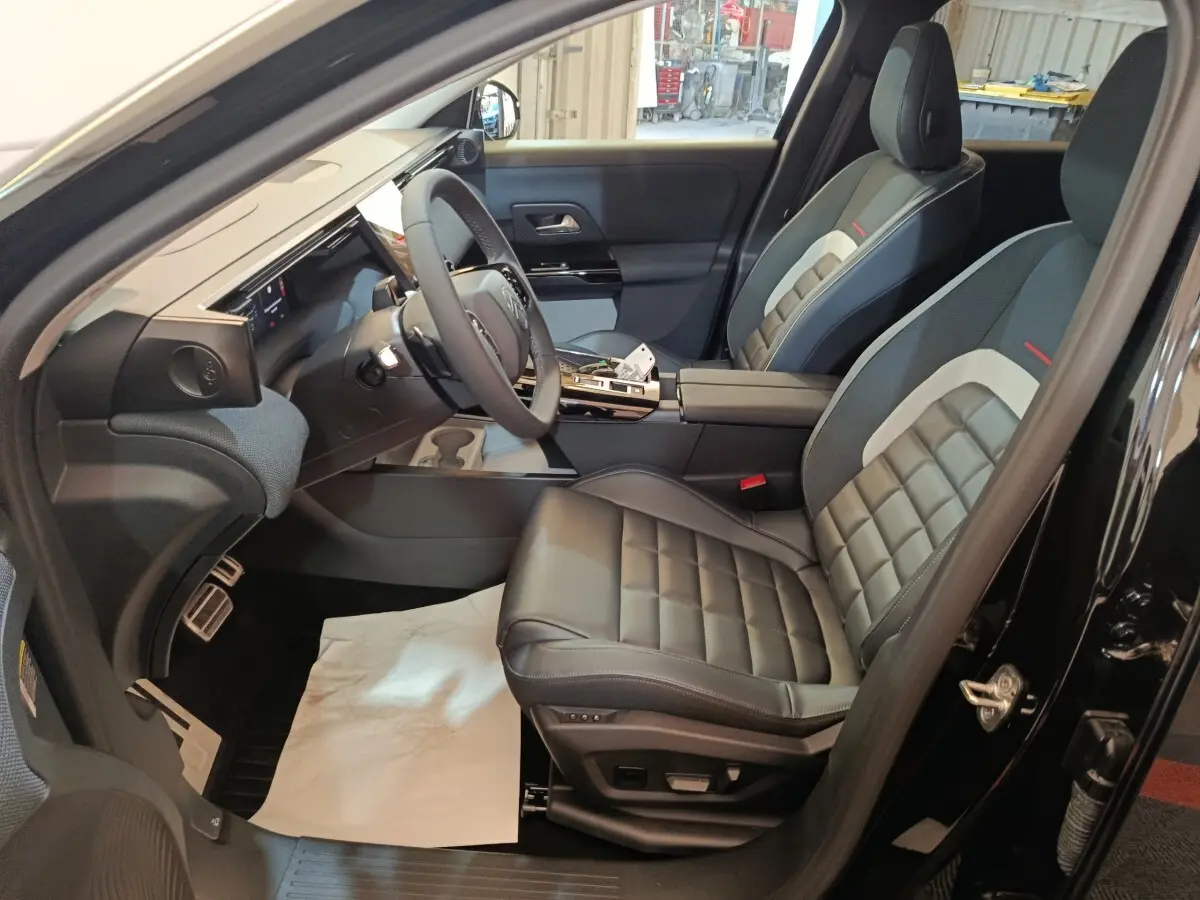 Vue intérieure côté conducteur de la Citroën C5 Hybride noire 2026, sièges cuir et tableau de bord moderne.