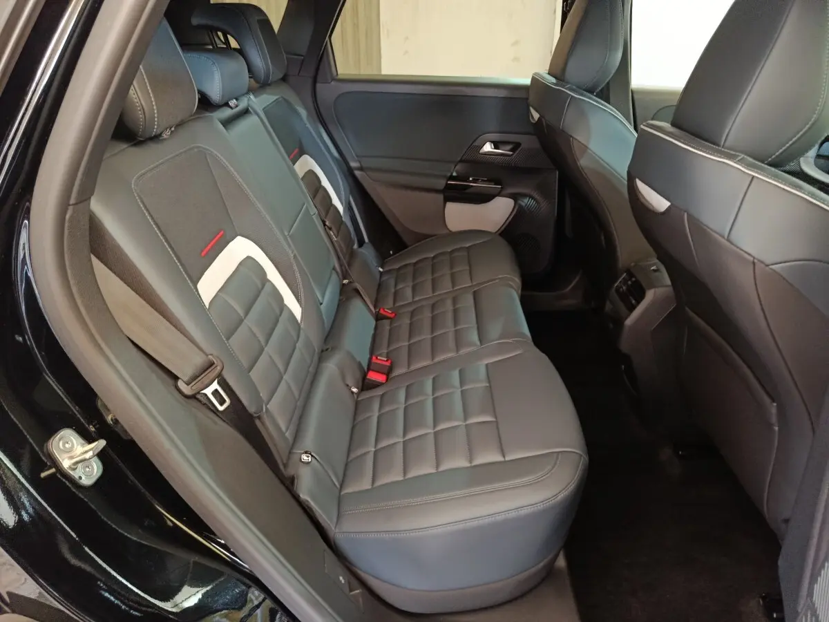 Vue intérieure côté gauche des sièges arrière noirs avec surpiqûres blanches et détails rouges du Citroën C5 Hybride 2026.