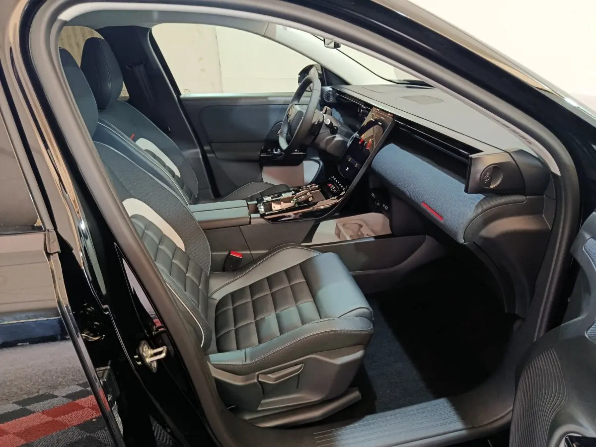 Intérieur avant droit d'une Citroën C5 Hybride noire 2026 avec sièges cuir et grand écran tactile central.