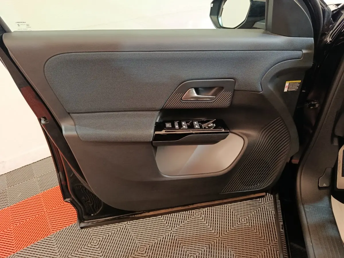 Vue intérieure côté gauche de la porte avant noire du Citroën C5 Hybride 145ch avec commandes de vitres et poignée intégrée.