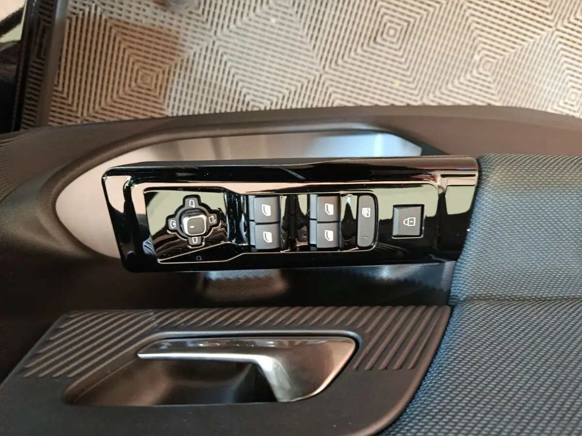 Gros plan sur la commande des vitres et rétroviseurs côté conducteur d’une Citroën C5 Hybride noire, intérieur tissu.