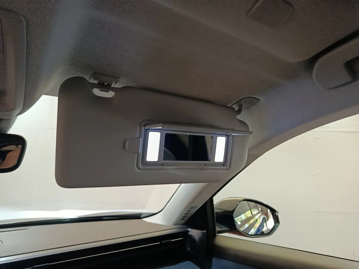 Intérieur de la Citroën C5 Hybride noir, vue côté passager avec pare-soleil rabattue et miroir éclairé.