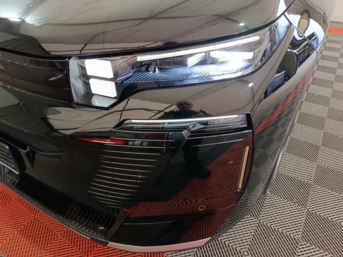 Gros plan sur le phare avant droit noir brillant du Citroën C5 Hybride 2026 avec détails LED et reflets.