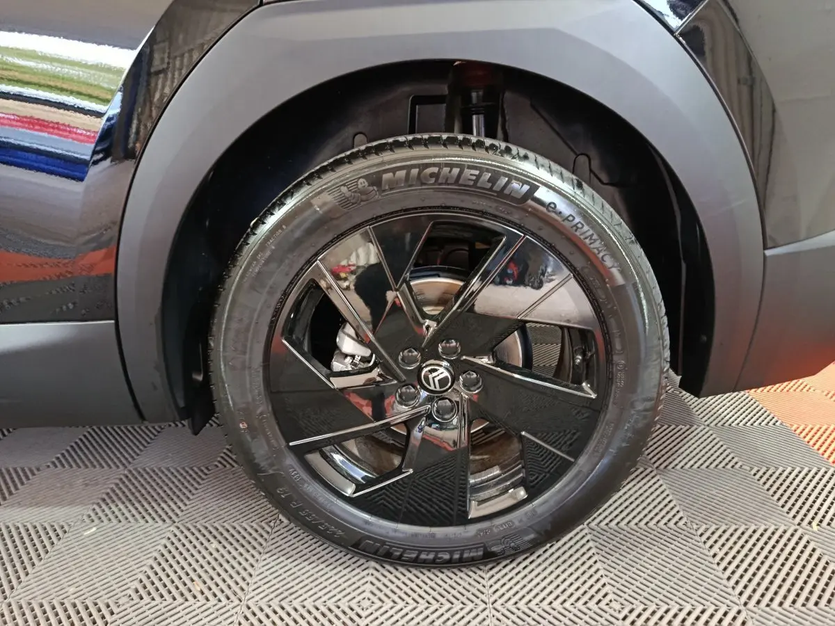Gros plan sur la roue avant gauche noire brillante d'une Citroën C5 Hybride 2026 avec jante stylisée et pneu Michelin.