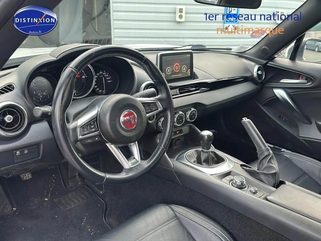 Intérieur noir de la FIAT 124 Spider 2017 vu côté conducteur, volant cuir multifonctions et boîte manuelle visible.