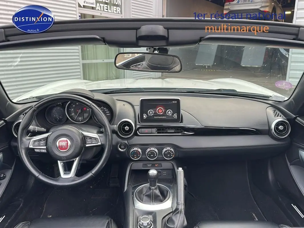Vue intérieure frontale du tableau de bord noir de la FIAT 124 Spider Lusso 2017 avec volant cuir multifonctions et écran tactile.