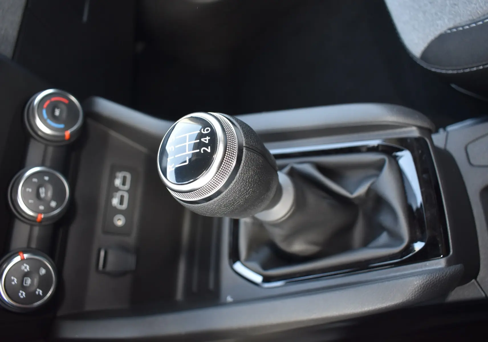 Le levier de vitesse manuel de la Renault Clio V TCE 90 gris, avec les commandes de climatisation en arrière-plan.