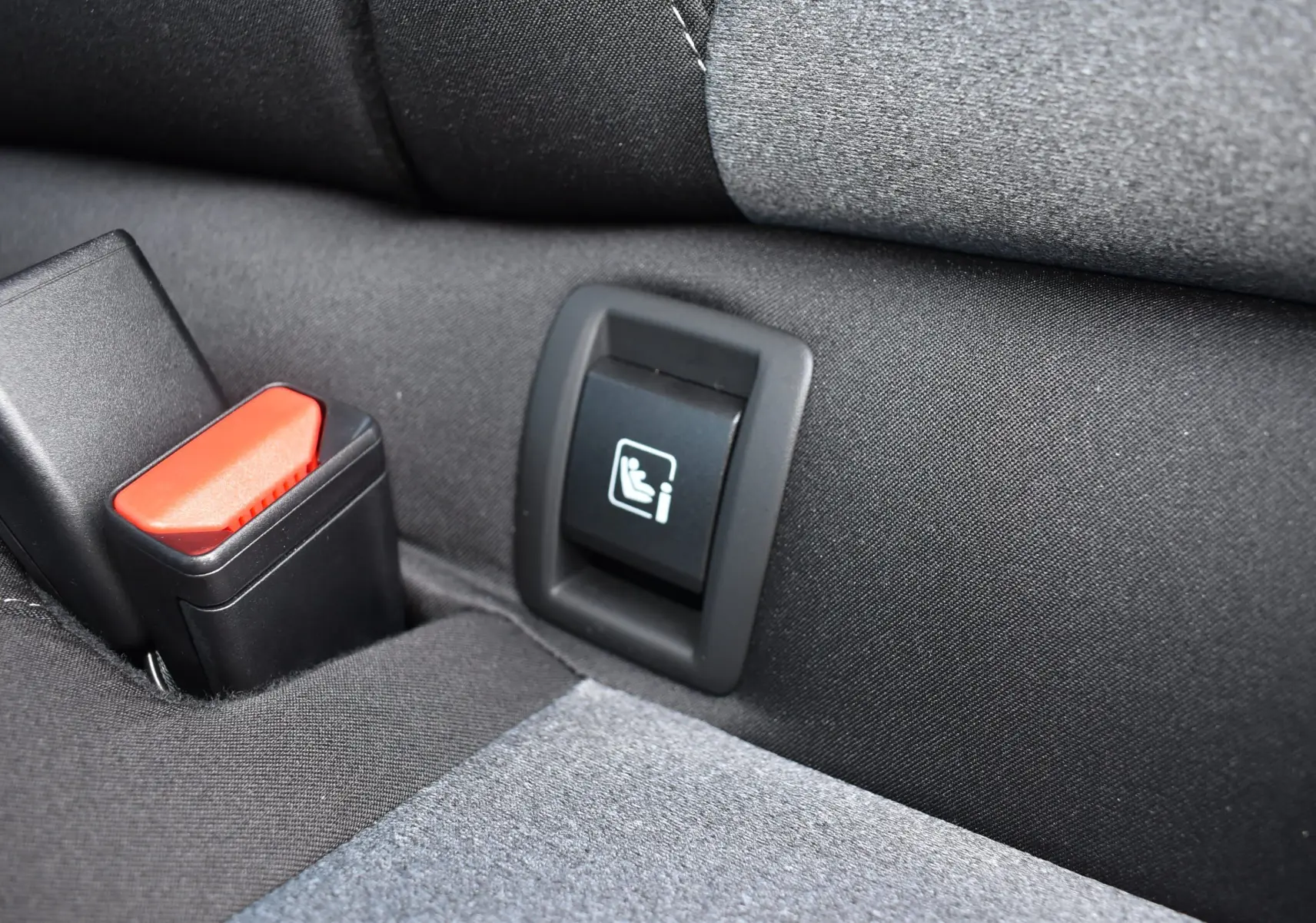 Gros plan sur la boucle de ceinture et l'ancrage ISOFIX arrière d'une Renault Clio V gris tissu.