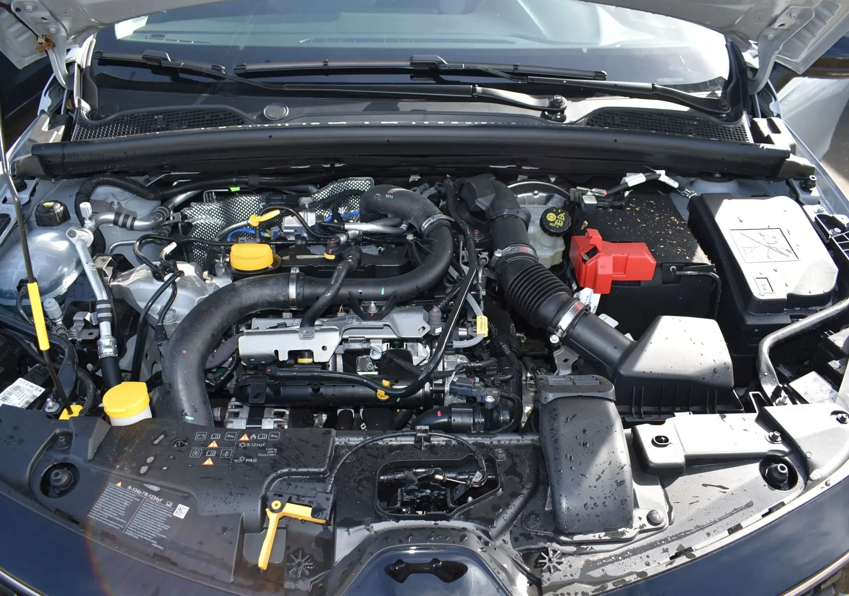 Moteur essence Renault Clio V TCE 90 gris 2024 vu de dessus avec capot ouvert et éléments moteurs visibles.