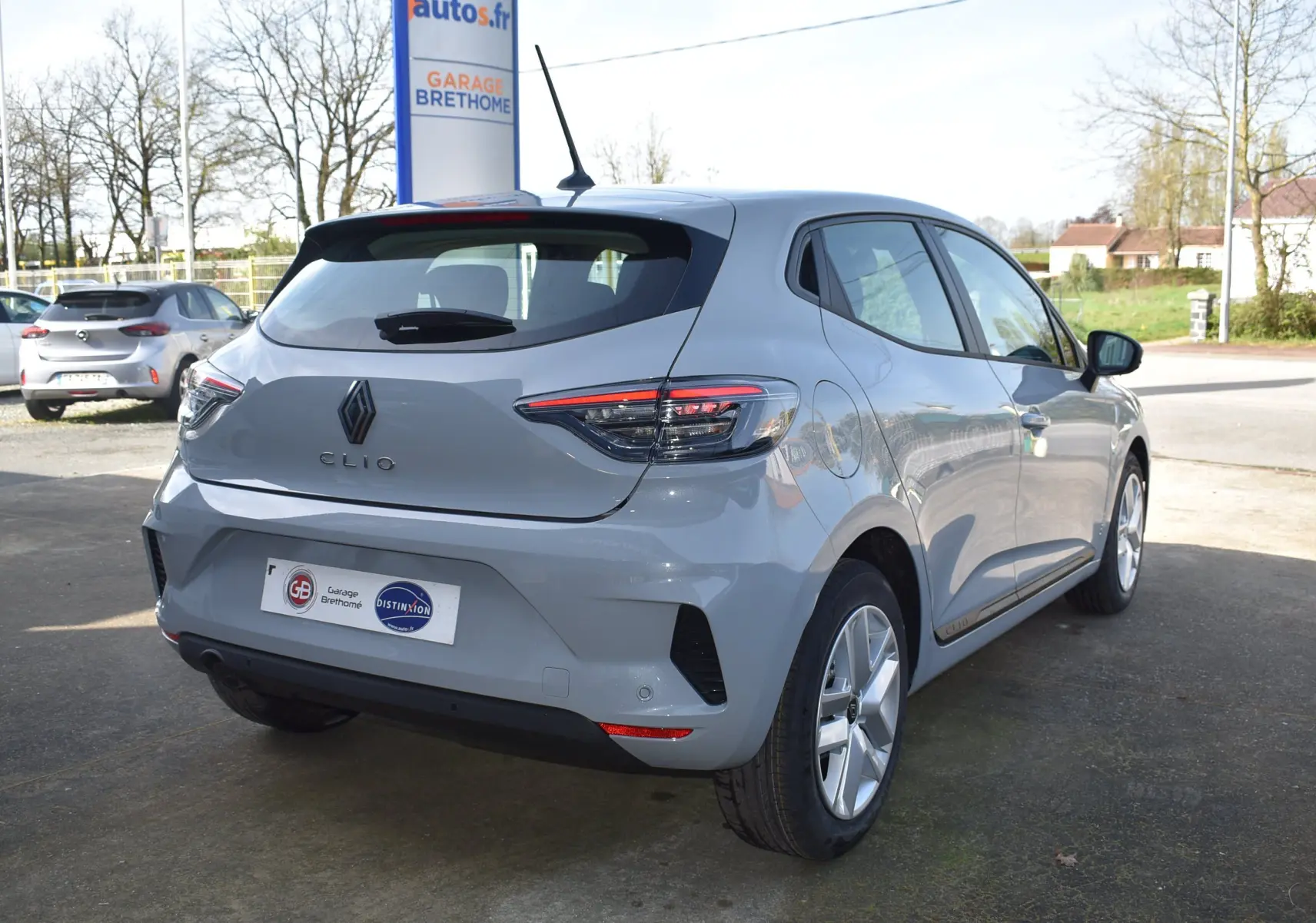 Vue 3/4 arrière droite d'une Renault Clio V gris clair 2024 avec feux arrière LED et jantes alliage.