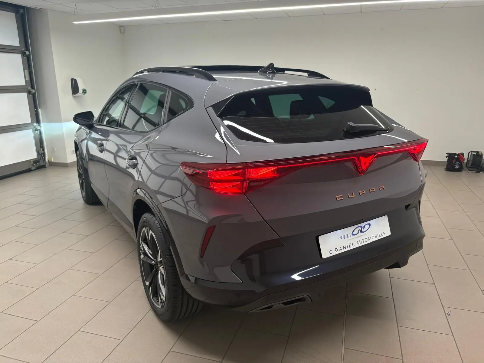 Vue 3/4 arrière droite du CUPRA Formentor gris Graphène 2025 avec toit ouvrant panoramique et jantes alliage 18 pouces.