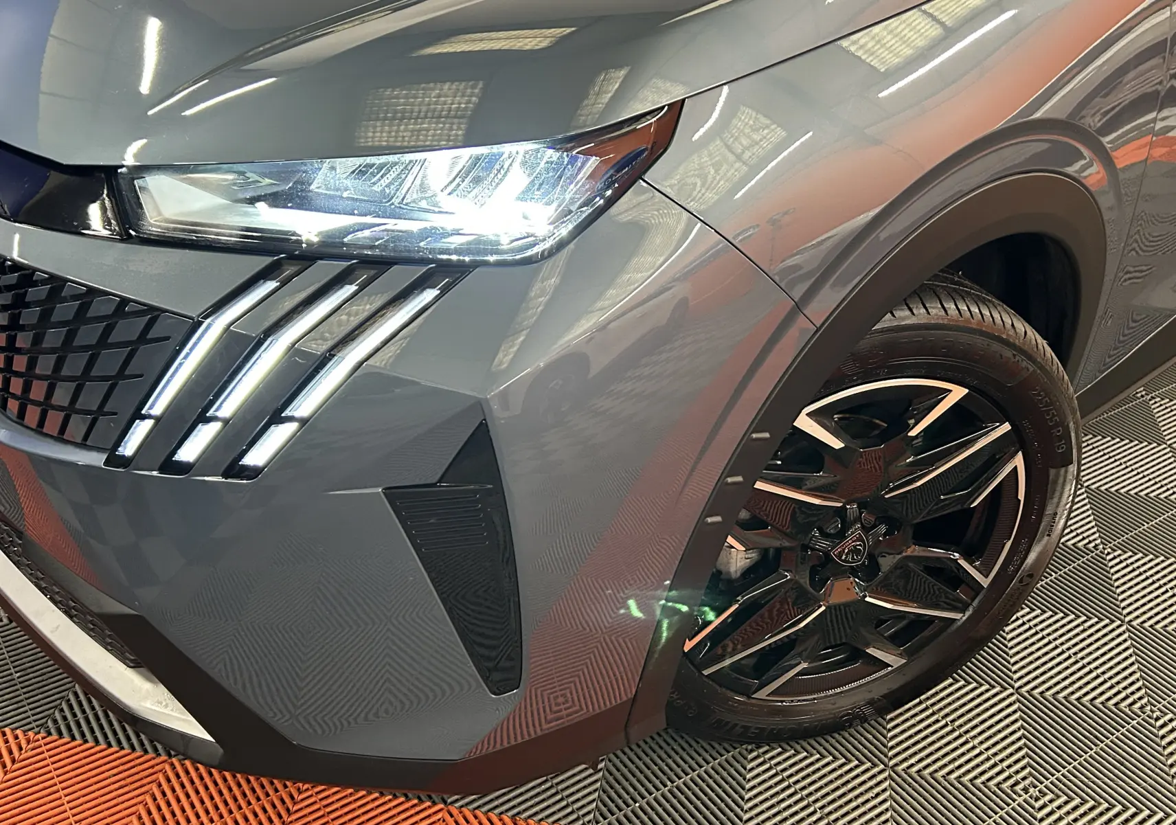 Gros plan sur l'avant droit bleu Ingaro du Peugeot 3008 III Hybrid avec phares LED et jante noire biton.