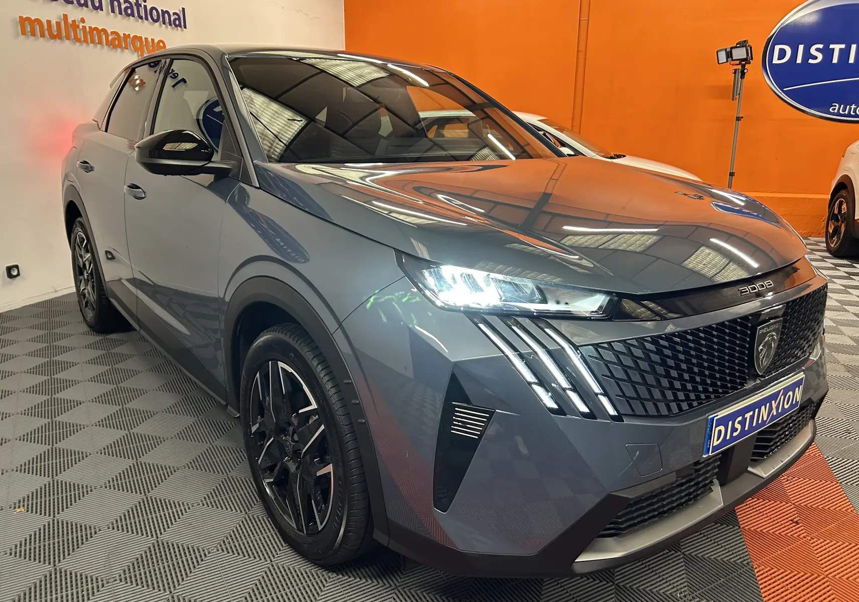 Peugeot 3008 III Hybrid bleu Ingaro en 3/4 avant droit, avec phares LED et calandre distinctive en intérieur showroom.