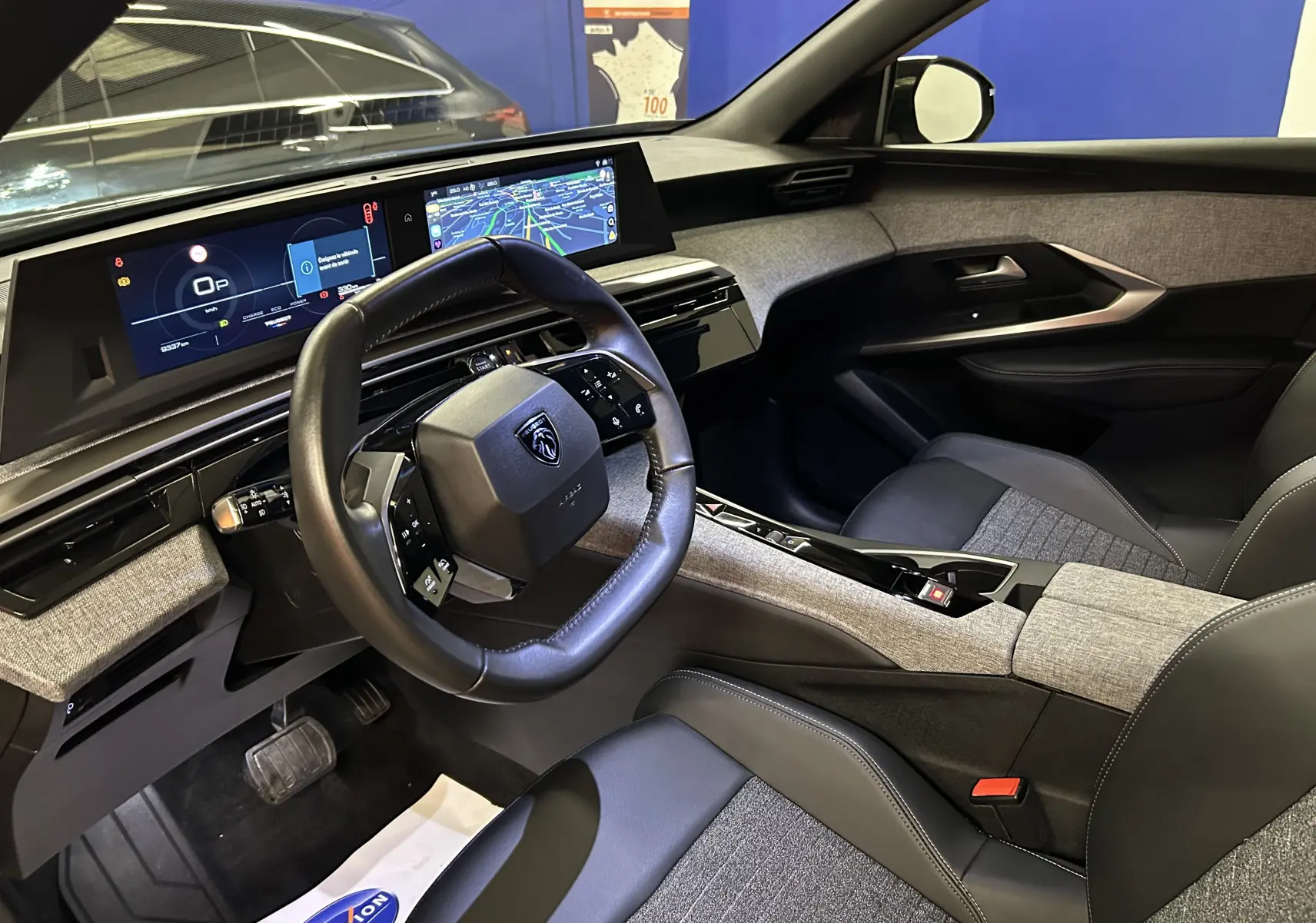 Vue intérieure côté conducteur du Peugeot 3008 Hybrid 2025, avec volant compact et tableau de bord numérique moderne.