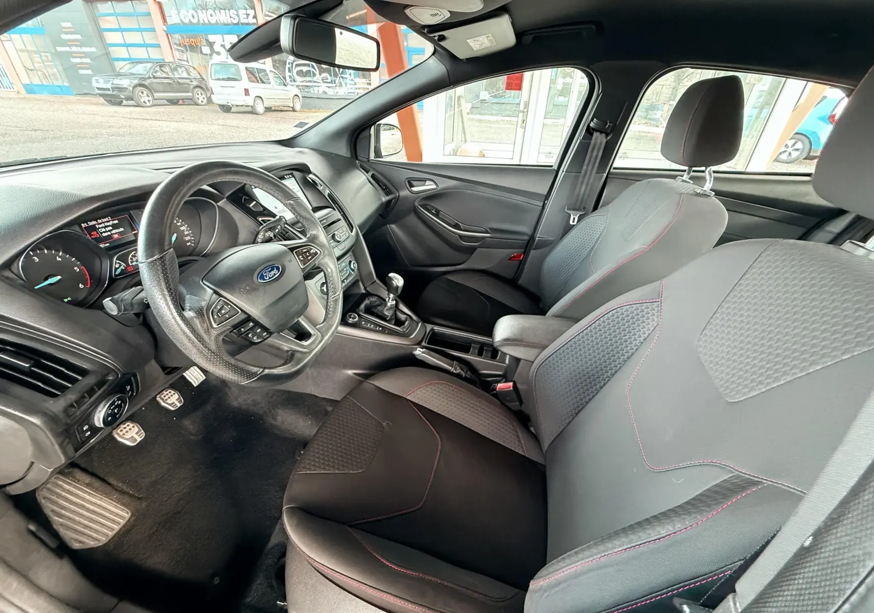 Gros plan sur les commandes de régulateur de vitesse au volant noir d'une Ford Focus gris 2018, version ST Line.