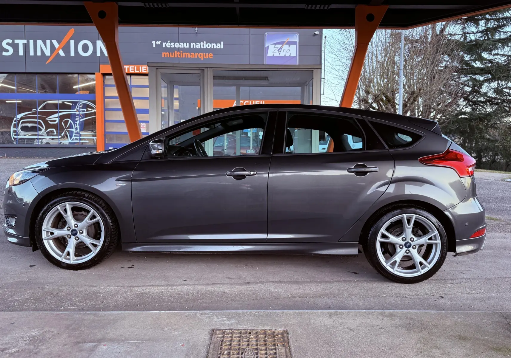 Vue de profil côté gauche d'une Ford Focus 1.5 TDCI 120 ST Line grise avec jantes alliage 18 pouces, cinq portes.