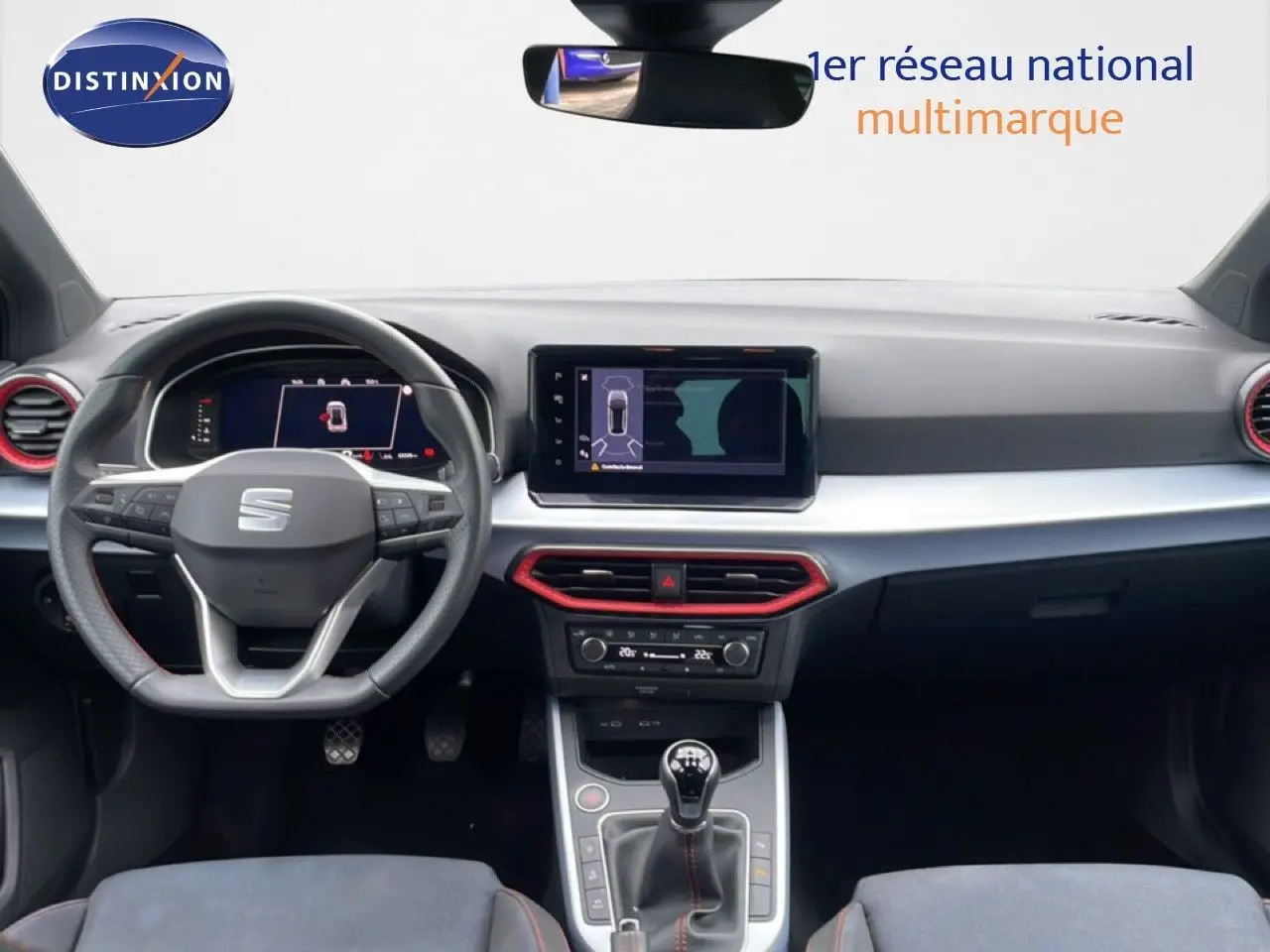 Vue intérieure frontale du tableau de bord du SEAT Arona 2025 avec volant multifonction et touches rouges autour des aérateurs.