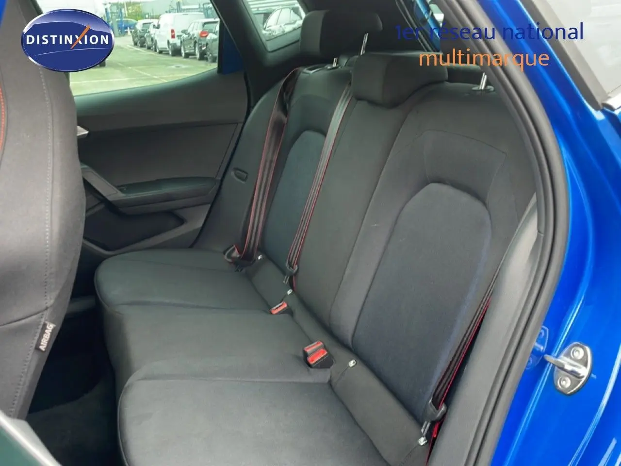 Vue intérieure côté droit sur la banquette arrière tissu noir avec ceinture rouge d'un SEAT Arona bleu saphir métallisé.