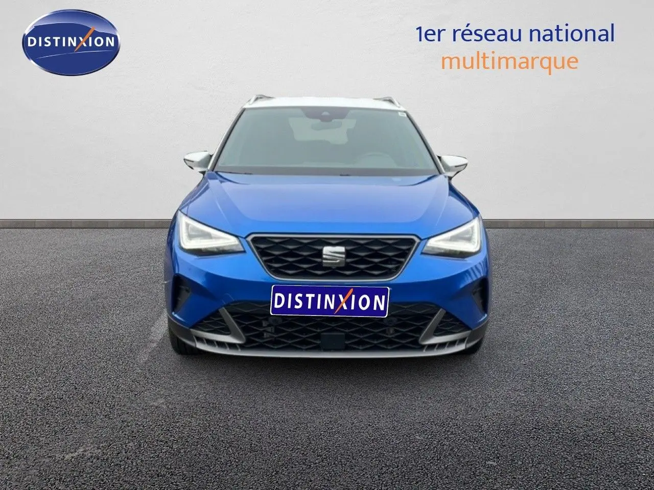 Vue avant d'un SEAT Arona bleu saphir métal avec toit blanc, mettant en valeur sa calandre et ses phares LED.