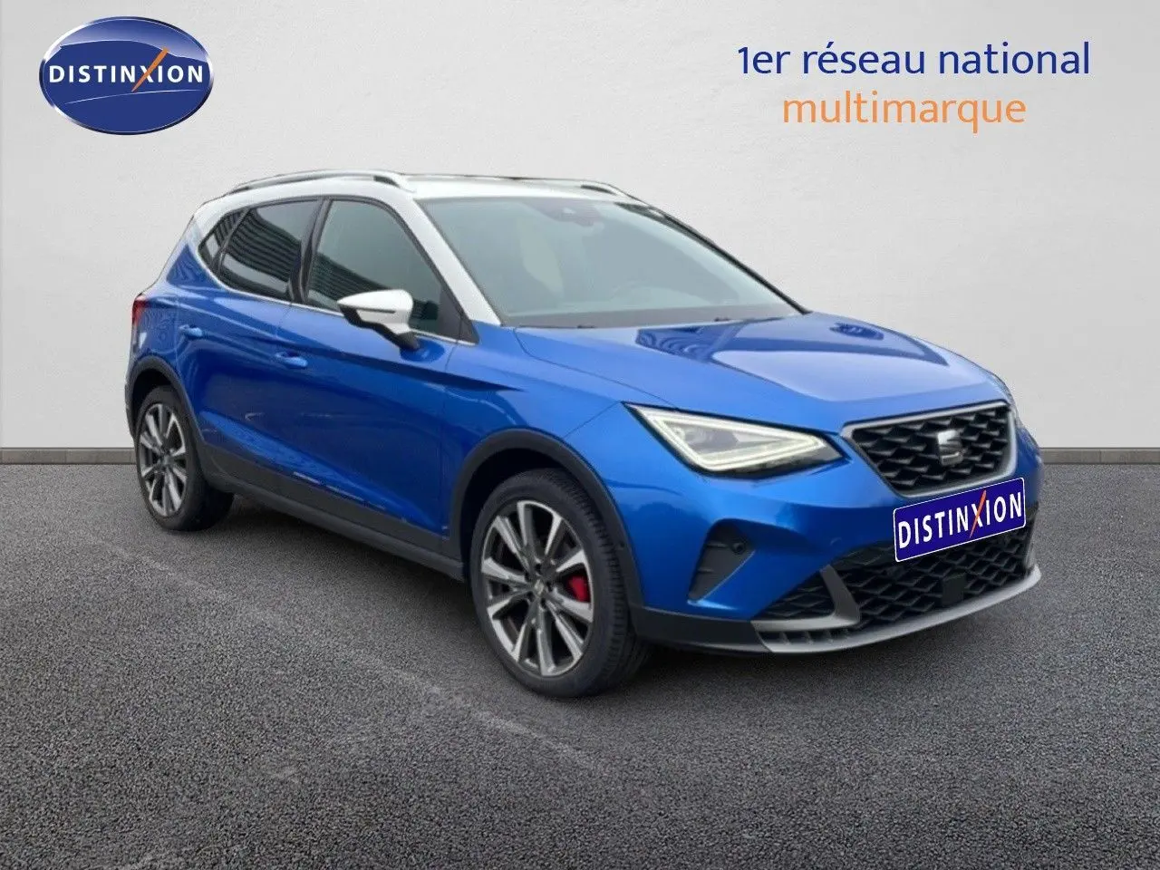 Vue 3/4 avant gauche d’un SEAT Arona bleu saphir métallisé avec toit blanc et jantes alliage, sur fond neutre.