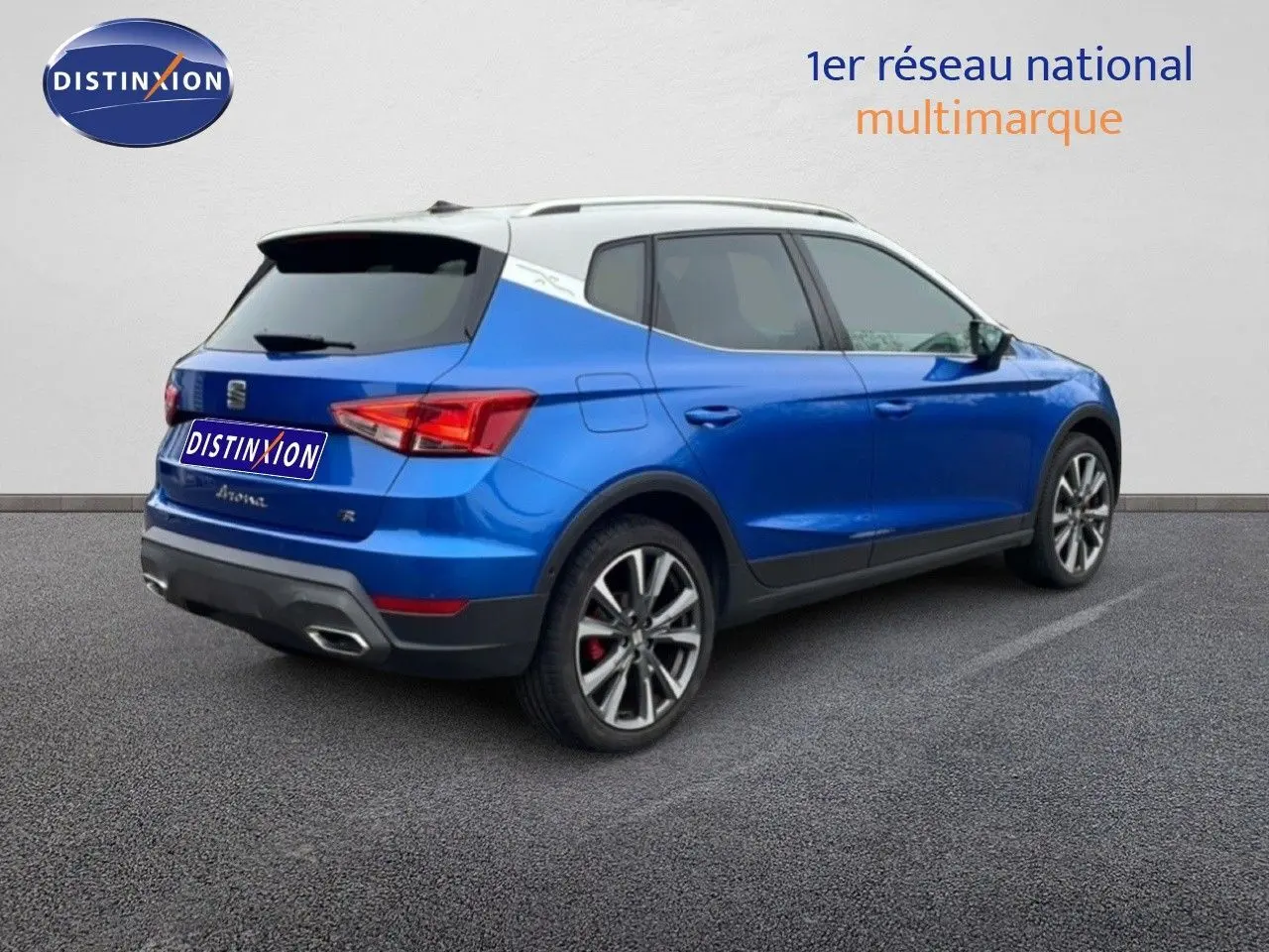 Vue 3/4 arrière droite d’un SEAT Arona bleu saphir métal avec toit blanc et jantes alliage distinctives.