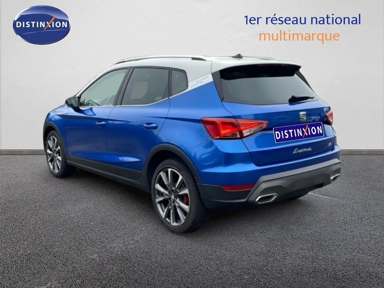 Vue 3/4 arrière d’un SEAT Arona bleu saphir métal avec toit blanc et jantes alliage, sur fond neutre.
