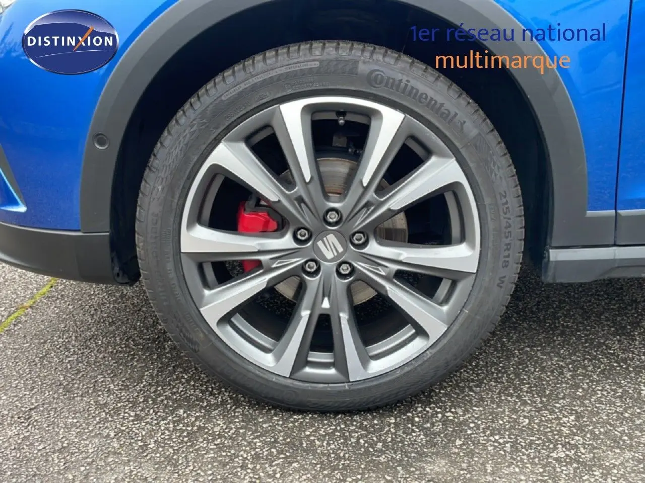 Gros plan sur la roue avant droite d’un SEAT Arona bleu saphir métal avec étrier de frein rouge et jante alliage.