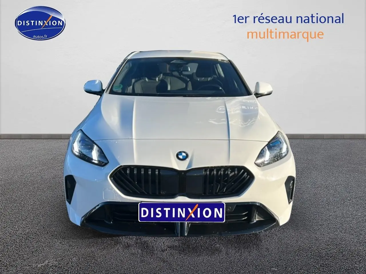 Vue avant d'une BMW Série 1 blanche Alpine avec calandre noire et phares LED allumés sur fond neutre.