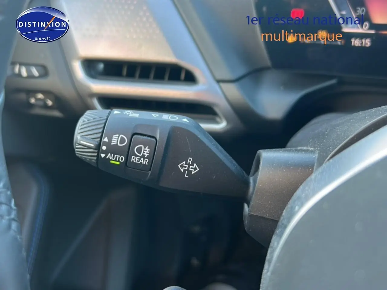 Gros plan sur la commande des phares et clignotants à gauche du volant dans l’habitacle d’une BMW Série 1 blanche.