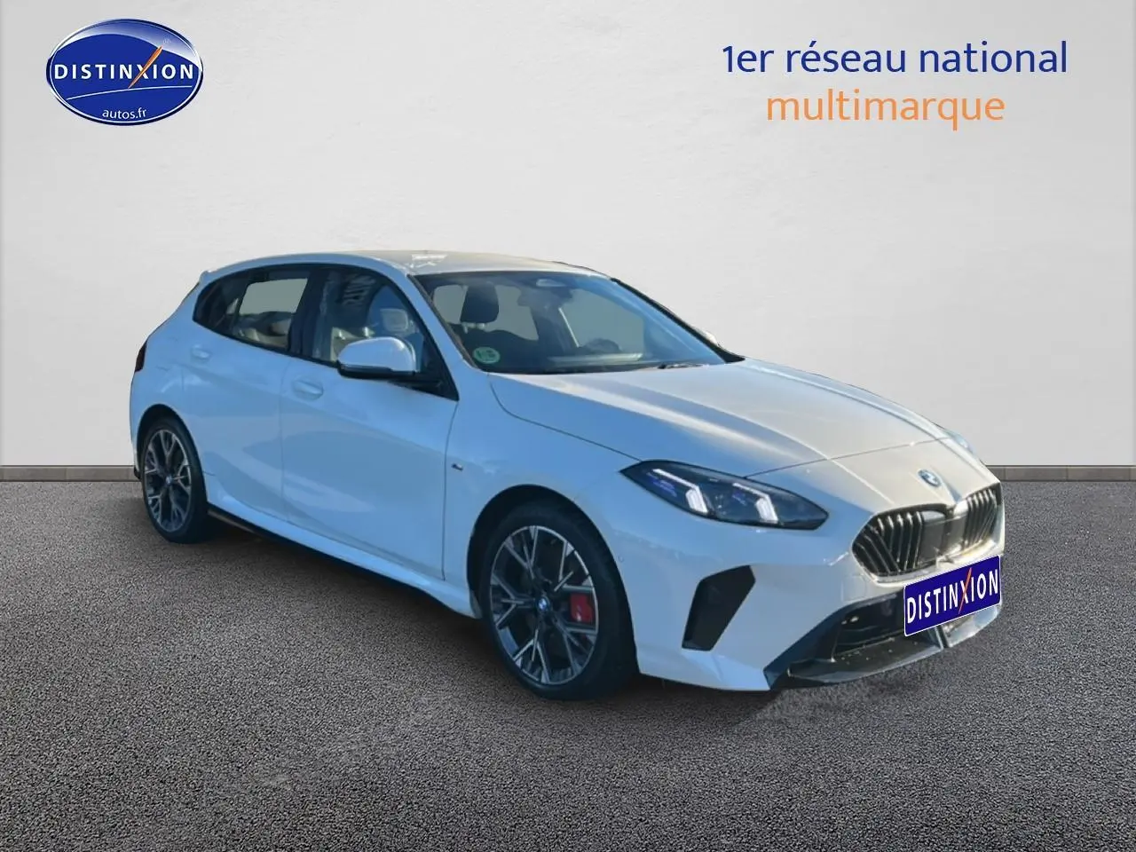 BMW Série 1 blanc alpin vue 3/4 avant droit avec jantes 18 pouces bicolores et calandre M sport.