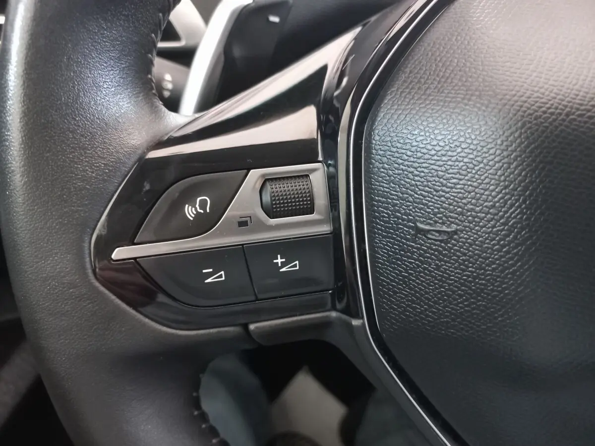 Gros plan sur les commandes gauche du volant noir du Peugeot 3008 2022, avec boutons de volume et commande vocale.