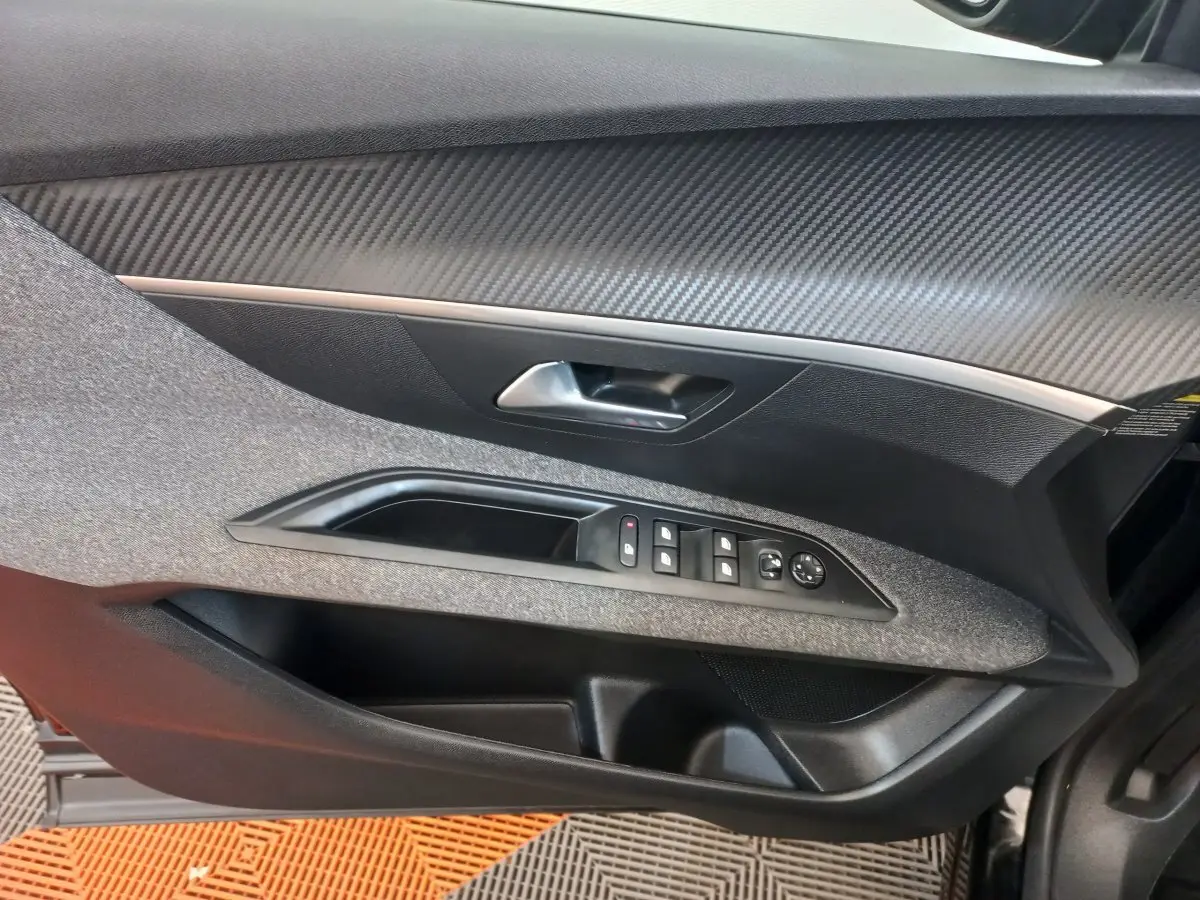 Vue intérieure côté gauche de la porte d'une Peugeot 3008 noire 2022, avec commandes de vitres et poignée argentée.