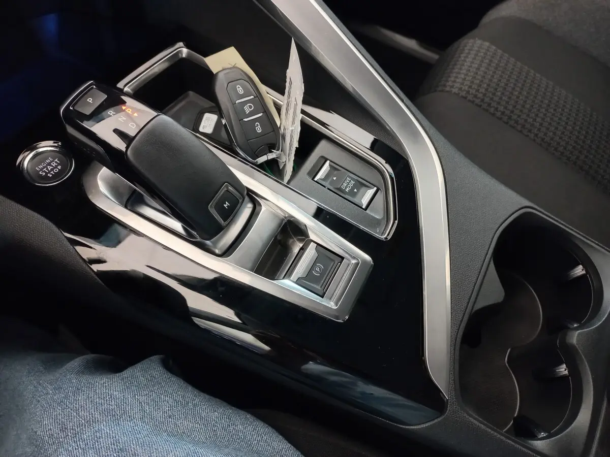 Gros plan sur la console centrale noire du Peugeot 3008 avec levier de vitesse automatique et clé intelligente posée.