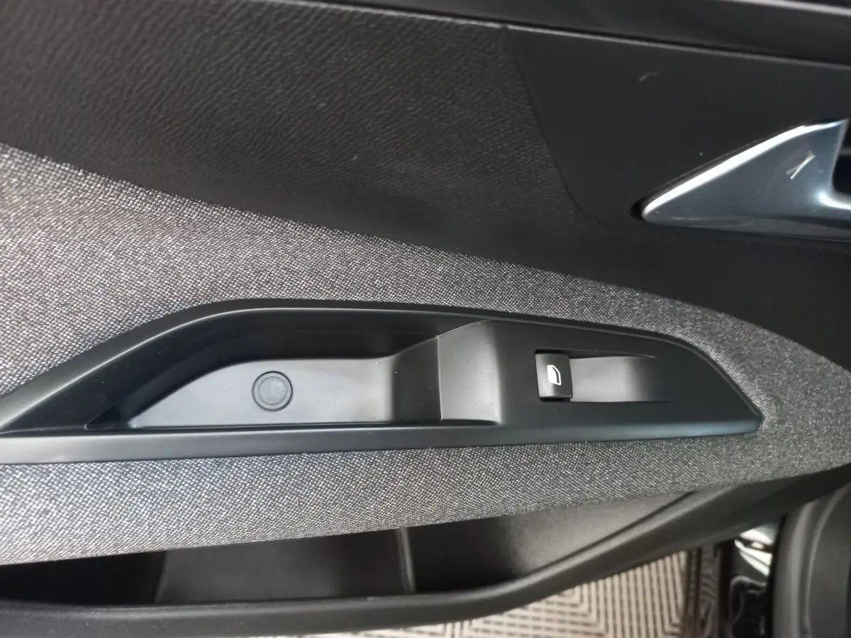 Détail de la commande de lève-vitre côté conducteur sur la porte intérieure du Peugeot 3008 noir, finition Active Pack.