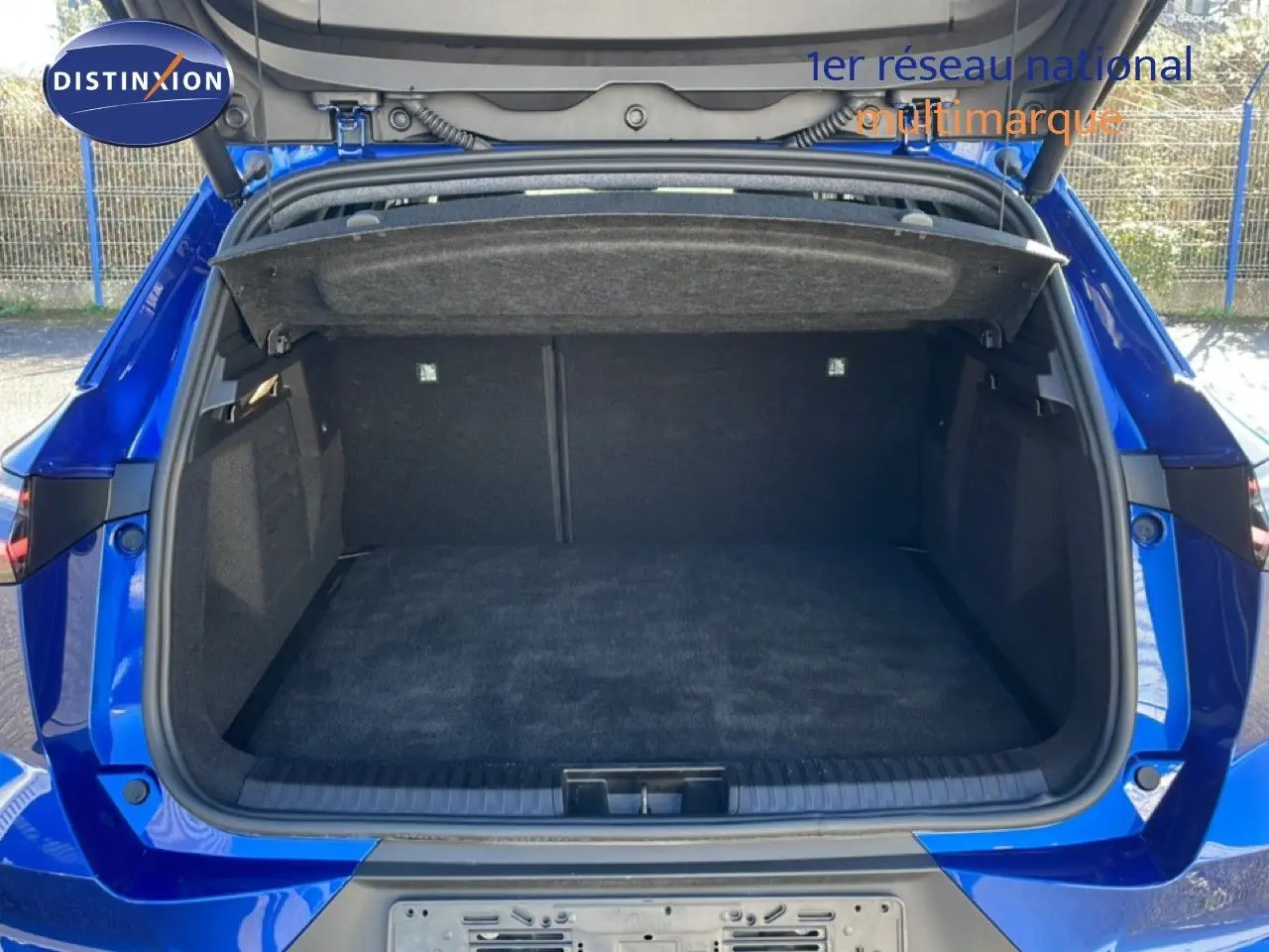 Coffre ouvert vu de l'arrière d'une Renault Symbioz bleu iron metal, montrant un espace de chargement propre et spacieux.