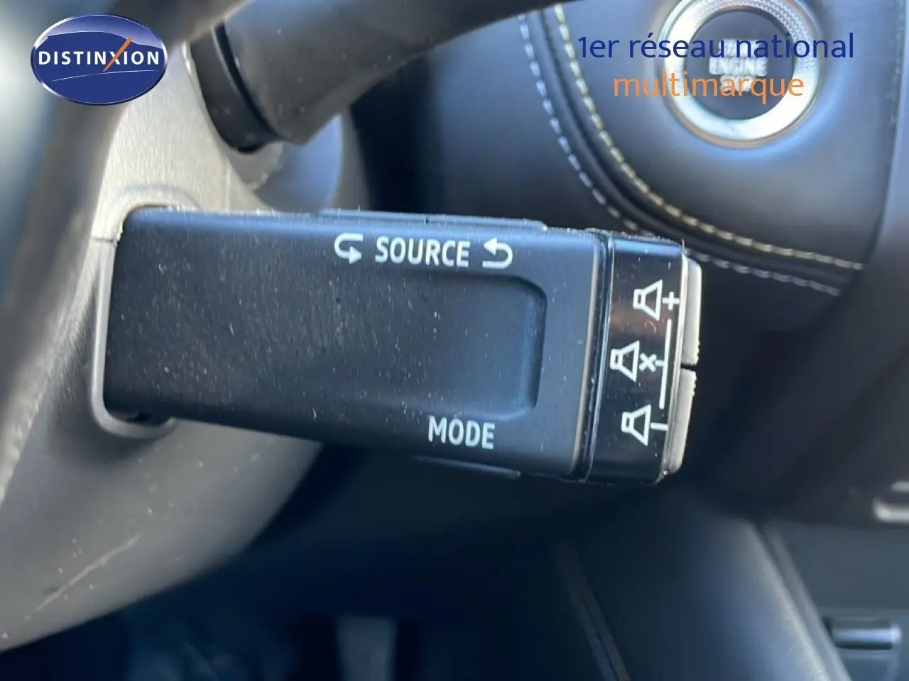 Gros plan sur la commande au volant du Renault Symbioz 2025, finition bleu iron metal, avec bouton source et mode visibles.