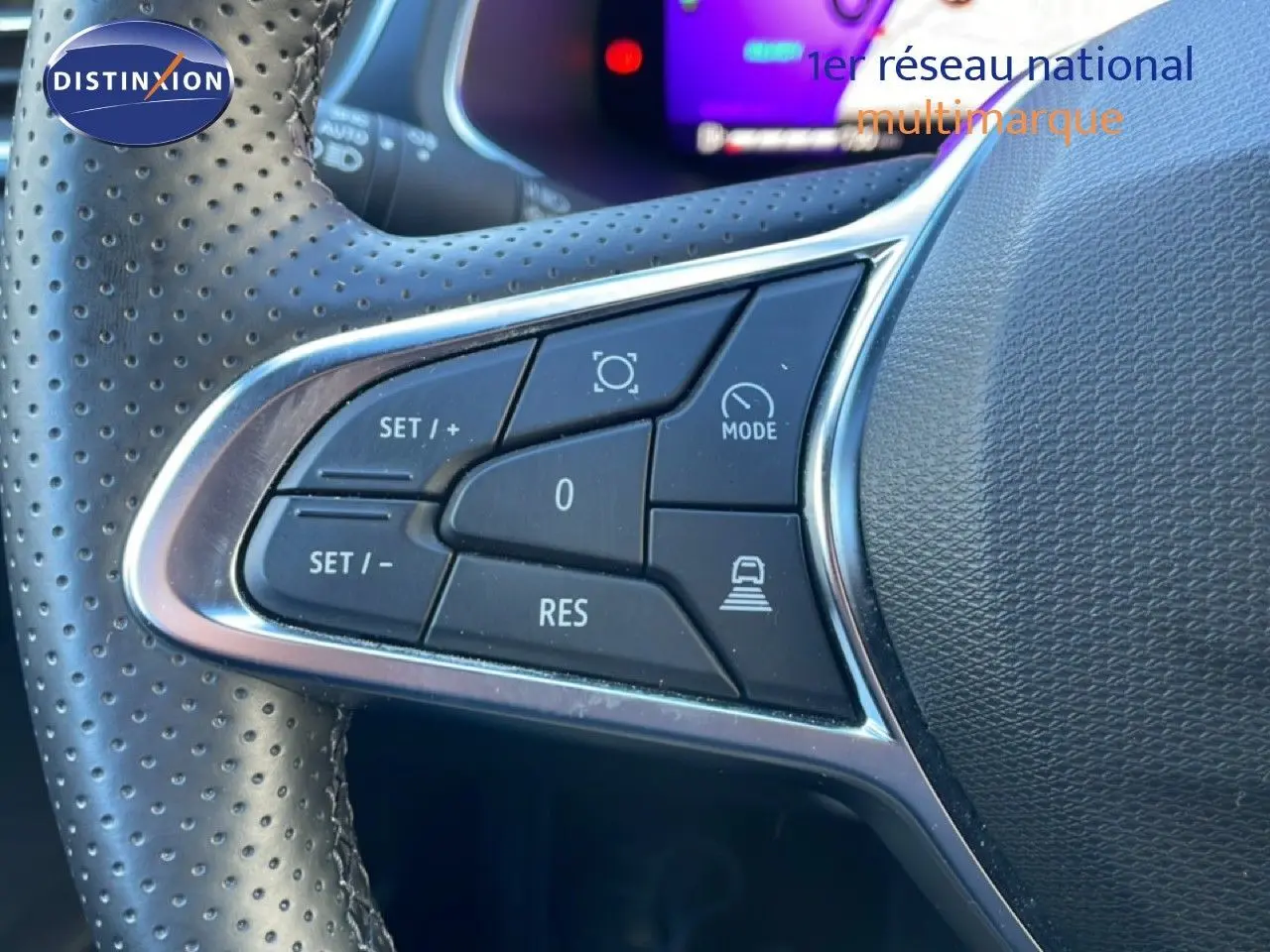 Gros plan sur les commandes au volant en cuir perforé du Renault Symbioz bleu iron metal, version hybride 2025.