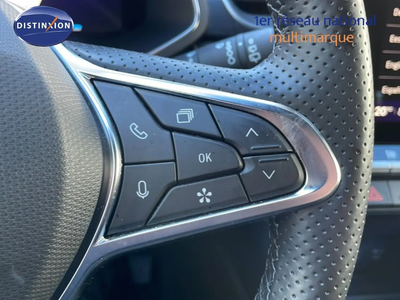 Gros plan sur les commandes multifonctions du volant en cuir perforé noir d'une Renault Symbioz bleu iron metal.