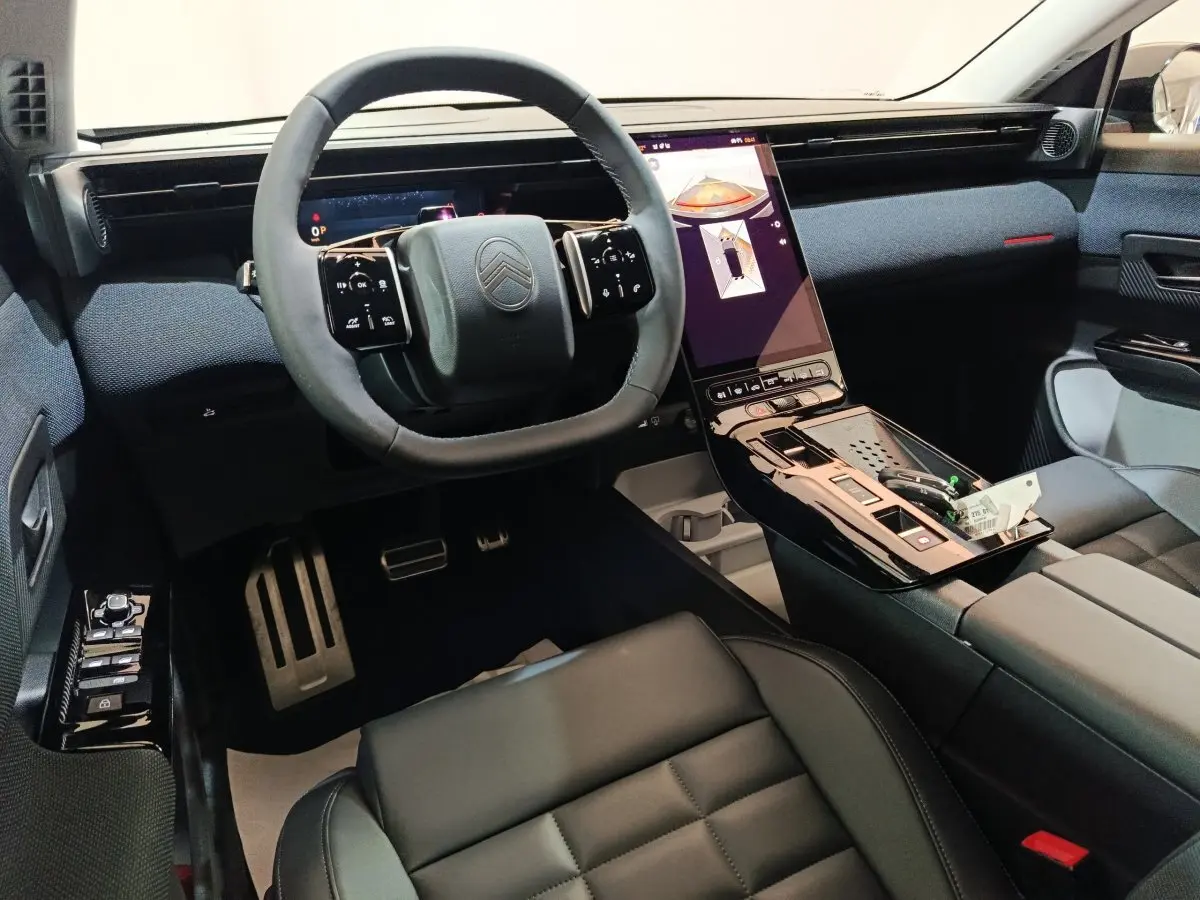 Intérieur de la Citroën C5 Hybride 2026, vue de face sur le volant cuir et l’écran tactile central vertical noir.