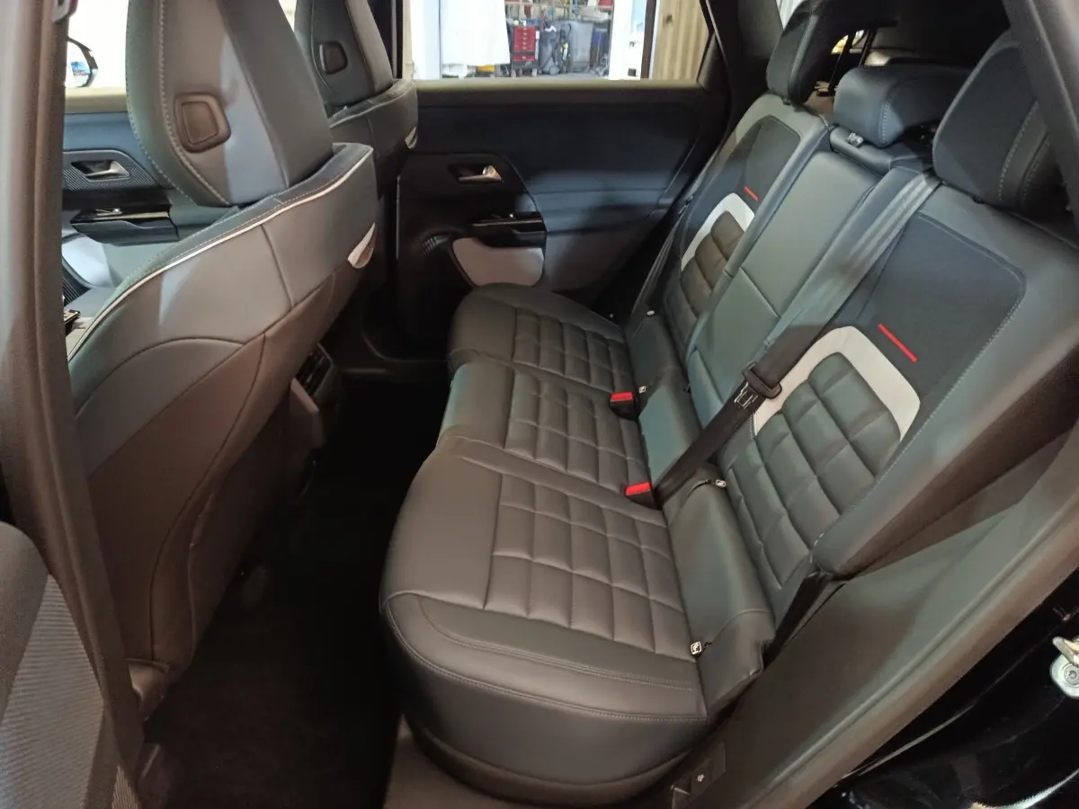 Vue intérieure côté droit des sièges arrière en cuir noir avec surpiqûres et détails gris et rouges d'une Citroën C5 Hybride 2026.
